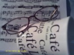 Music score with eyeglasses on top of cup on its side with Café Latte written on it.