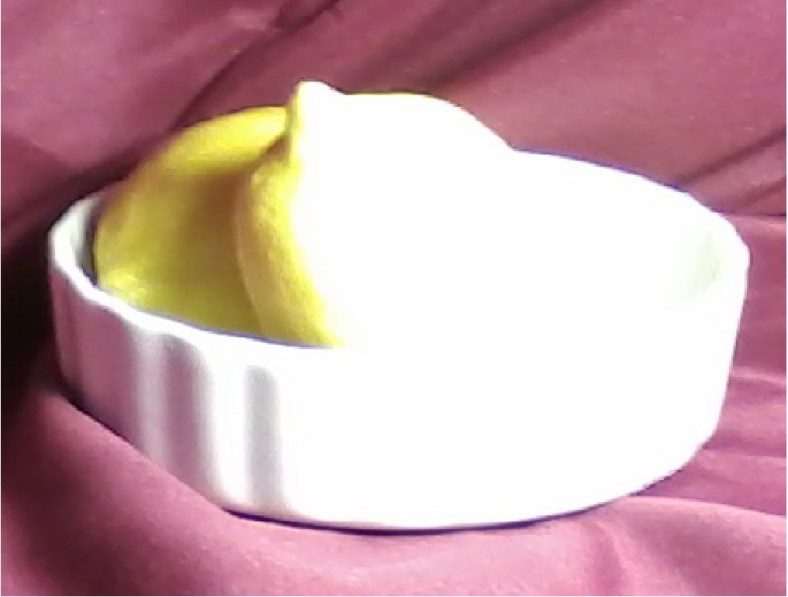 Two lemons in a ceramic dish with red faric draping